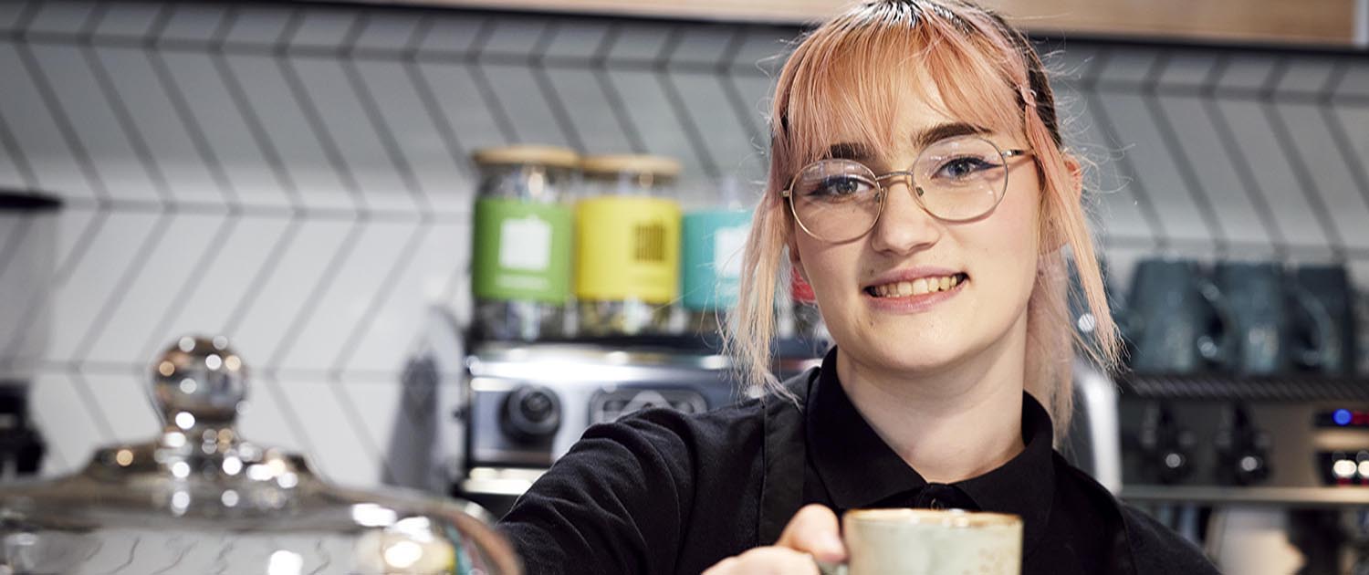 Barista Hannah holding coffee