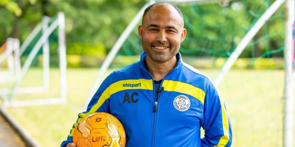 Adel stands with football in front of football pitch before his epic journey to Wembley